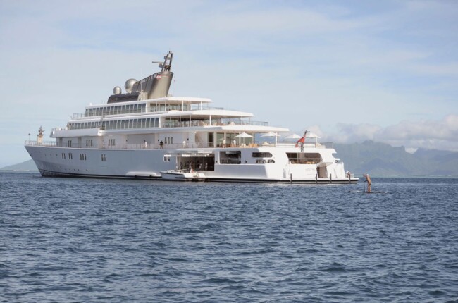 CORRECTION - A Tahitian on a paddleboard approaches the 138 meter Rising Sun yacht where former US president Barakl Obama his wife and friends spent the morning off the Island of Moorea, in the South Pacific, part of French Polynesia on April 14, 2017. Former US President Obama and his wife Michelle, US singer Bruce Springsteen, US actor Tom Hanks and TV personality Oprah Winfrey, spent two hours aboard the Rising Sun before leaving Tahiti. The Obamas left Tahiti after a one-month stay in French Polynesia. / AFP PHOTO / Mike LEYRAL / 