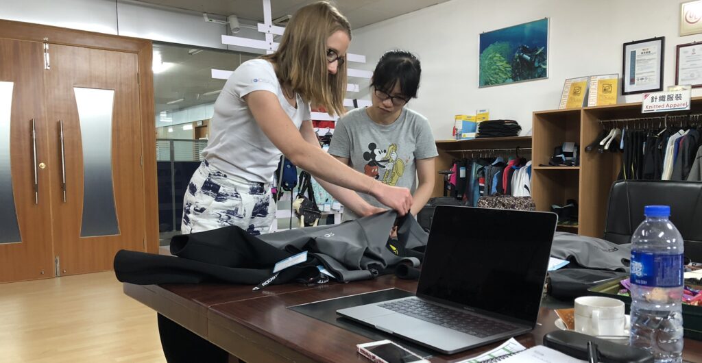 two people look at marine clothing designs on a table