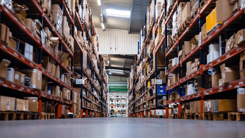 Inside a warehouse. Multiple shelves stocked with goods from VDM-Reya, Henri-Lloyd French marine distributor