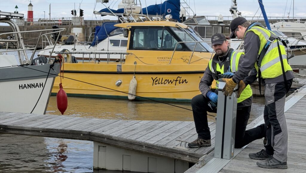 Two workers install new bollards at Watchet Marina