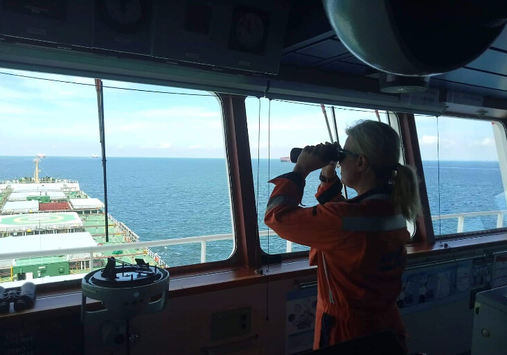 seafarer with binoculars at window
