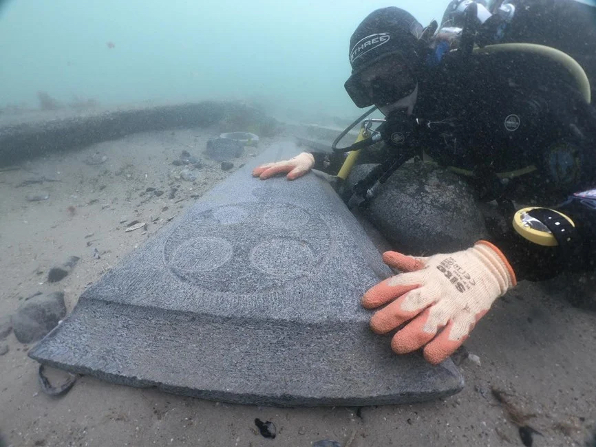 plongeur au plus ancien naufrage d'angleterre regardant une pierre tombale décorée