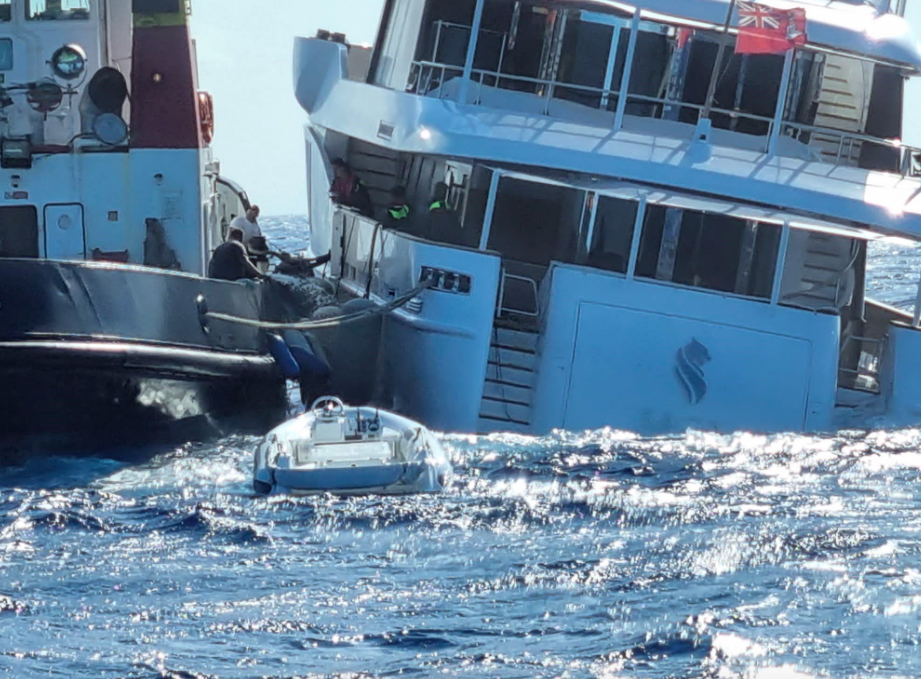 タグボートがモーター ヨットにロープを取り付け、モーター ヨットがイタリアの海岸線から沈みます。