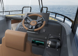 Cockpit of motorboat showing steering wheel, throttle and mobile phone charging pod, with views ahead of the sea and horizon.