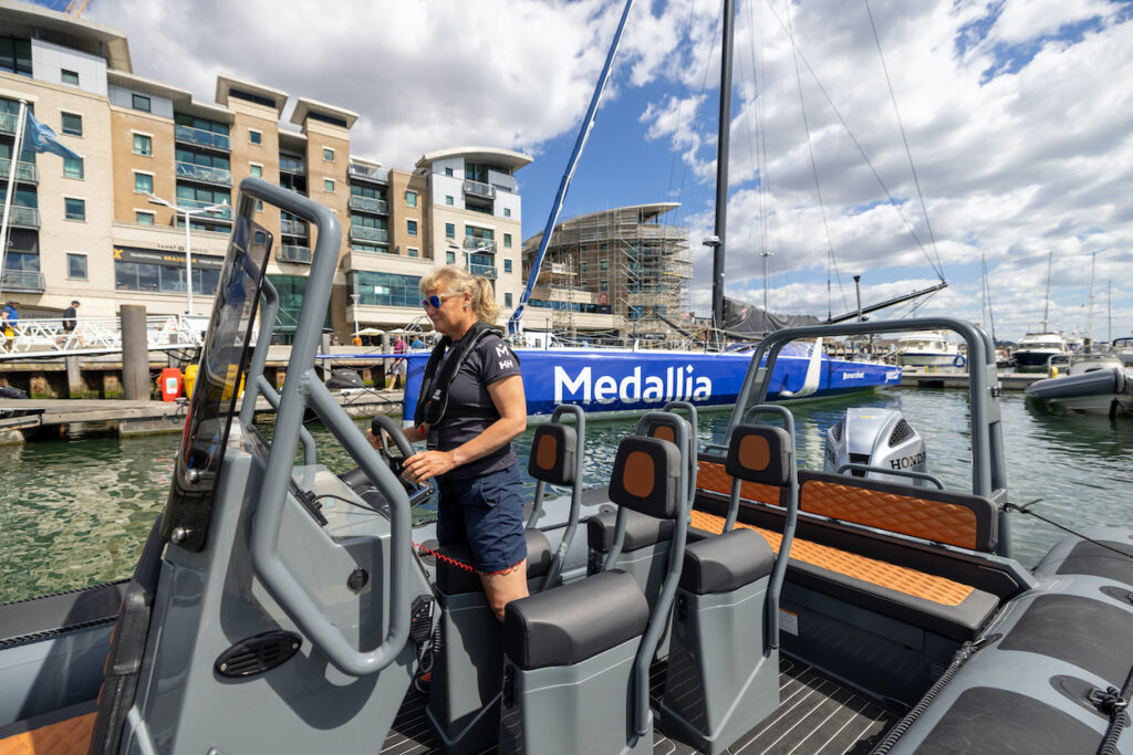 Woman standing up at the helm of a RIB docked in marina.