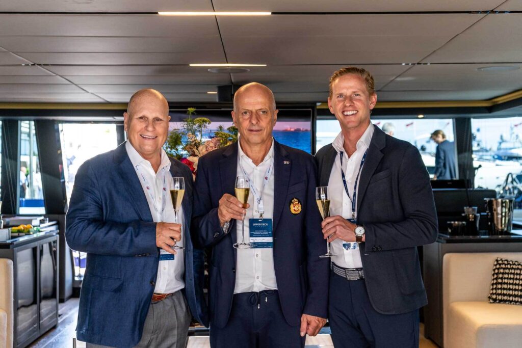 Three men smiling while holding glasses of champagne to celebrate their partnership.