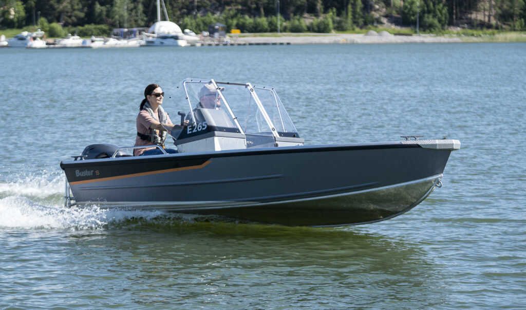 small motorboat with windshield and two people on board powers across a lake