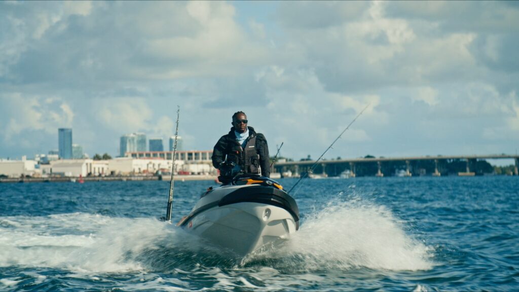 Man at helm of personal watercraft with fishing rods