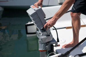 barefooted man attaching battery of electric outboard on the back of boat