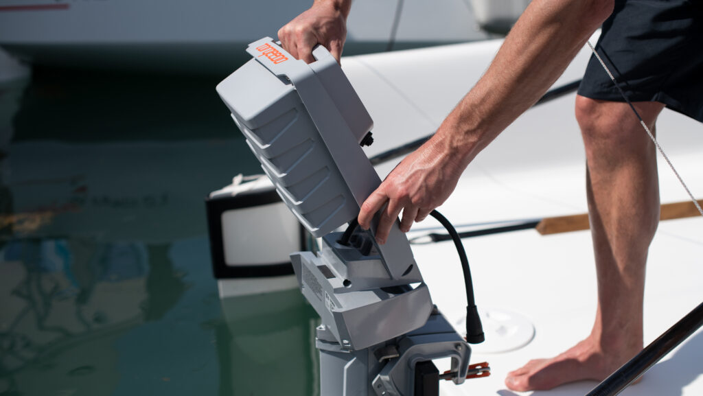 hombre descalzo conectando la batería del fuera de borda eléctrico en la parte trasera del barco