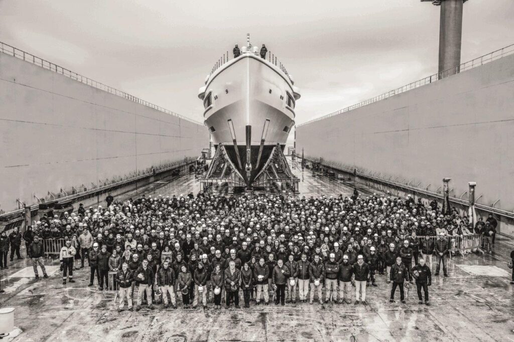 Crowd of people in front of the bow of a large motor yacht