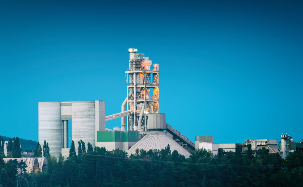 Edificio industriale della fabbrica di cemento francese sulla riva del fiume al crepuscolo del giorno sull'ora blu del cielo blu