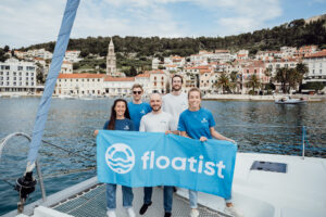 five people on the bow of a boat with a blue banner