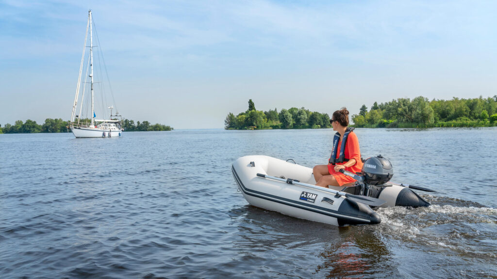 small inflatable boat with outboard travelling to larger yacht