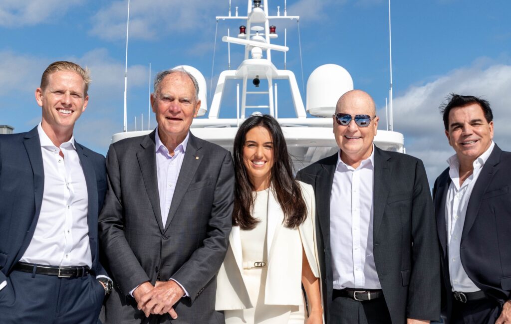 Four business people standing on the front of a large yacht
