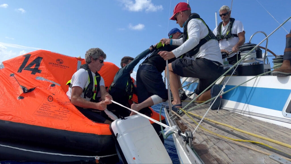 De bemanning van de Franse OGR-deelnemer Triana (66) FR assisteerde Stéphane Raguenes in het reddingsvlot voordat hij aan boord van de helikopter werd gehesen en voor medische hulp naar Madeira werd gevlogen. Krediet: OGR 2023 / Margault Demasles