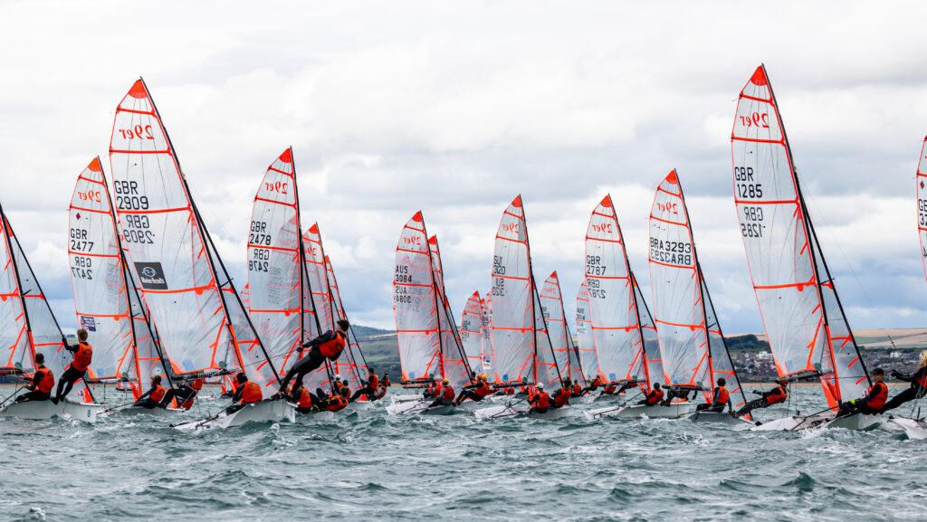 series of identical sailing boats competing in a race with choppy water