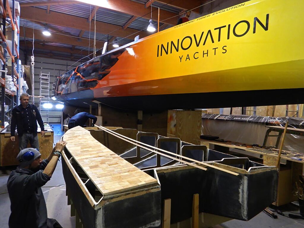 Yellow and orange hull of large yacht in indoor shipyard