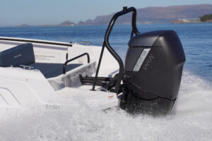 View of an electric outboard engine at the back of a motor boat that is speeding through the water.