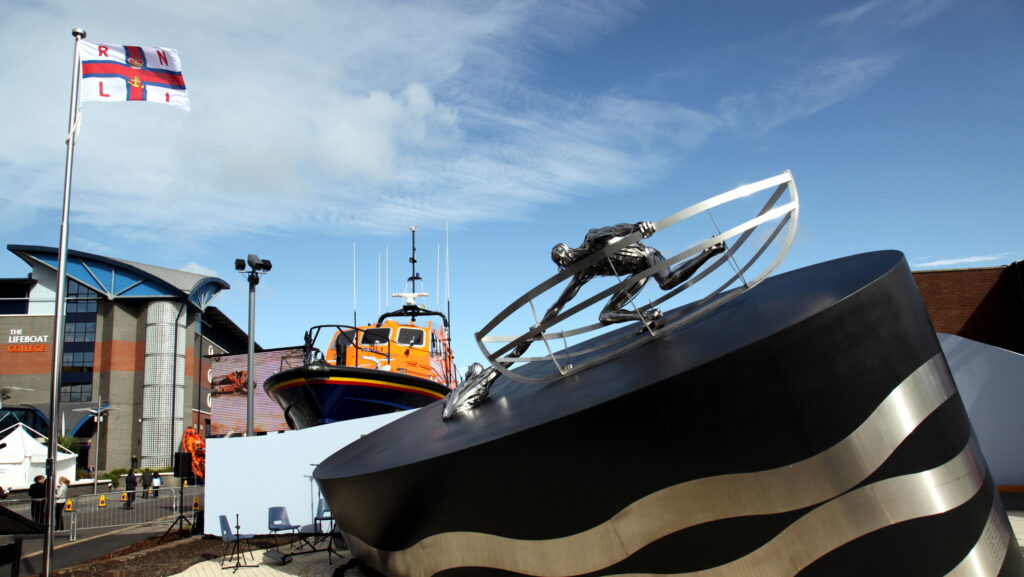 RNLI-Gedenkfeier. Das Bild zeigt die Gedenkstätte mit dem Lifeboat College dahinter. Poole. Flagge