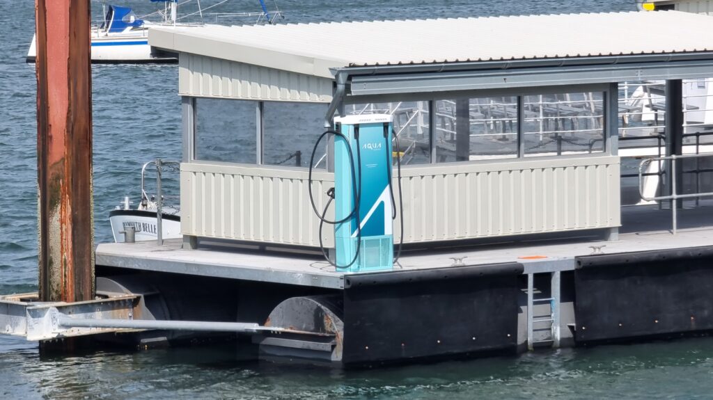 Punto de carga eléctrica sobre pontón flotante con ferry amarrado en el lado opuesto.