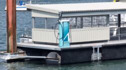 Borne de recharge électrique sur ponton flottant avec un ferry amarré du côté opposé.