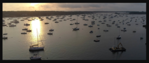 多くのレジャーボートが停泊している静かな湾に沈む夕日