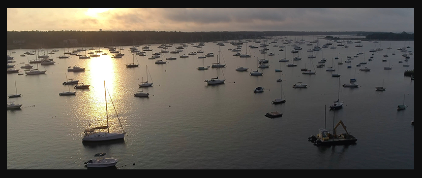 Sonnenuntergänge über einer ruhigen Bucht mit vielen Freizeitbooten vor Anker