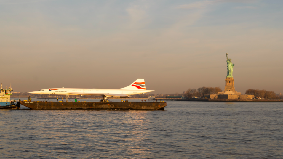 Concorde on barge passing by the Statue of Liberty