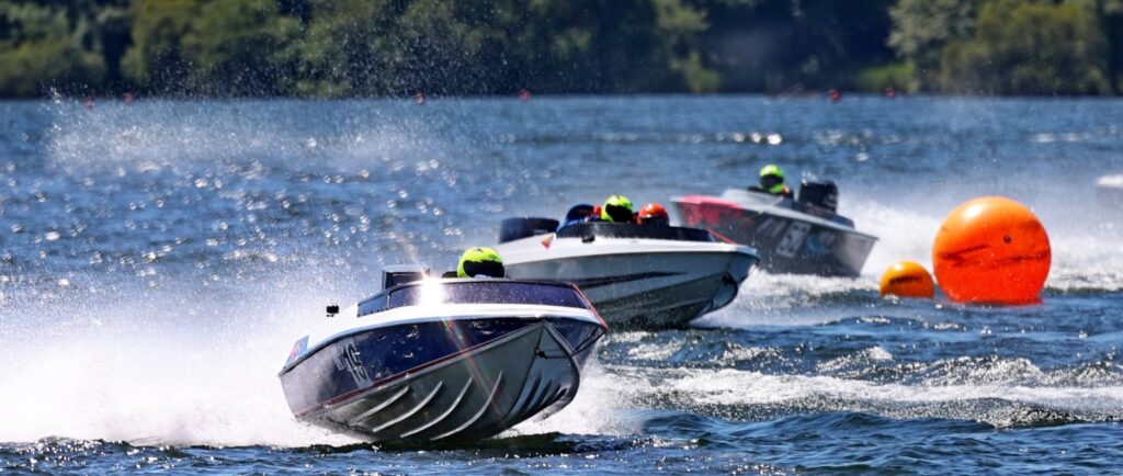 drie raceboten stuiteren over het water nadat ze een oranje boei hebben gerond