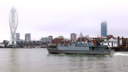 Le navire de guerre entre dans le port de Portsmouth avec la tour Spinnaker en arrière-plan