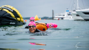 Zwemmers in roze mutsen met een grote boot op de achtergrond van SIBS swim