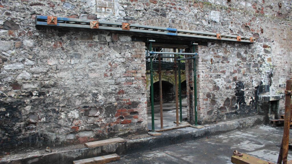 Über einer Tür in einem grauen Backsteingebäude wurde ein tragender Balken angebracht
