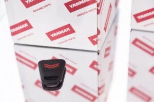 Sleutelhanger close-up naast de rode verpakking met het Yanmar-logo