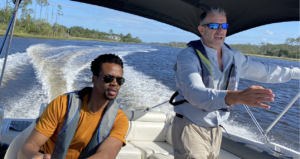 Twee mannen op een speedboot aan het roer, één man staat en wijst