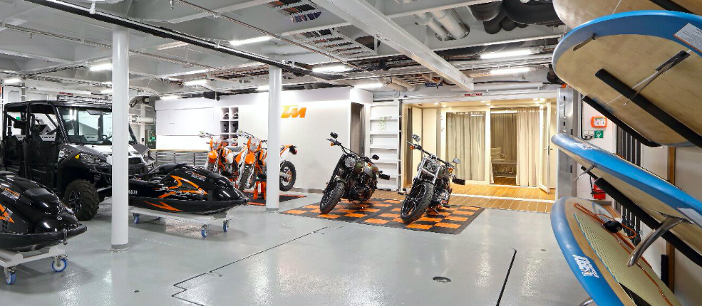 a selection of toys - motorbikes, paddleboards and more - in a superyacht's garage