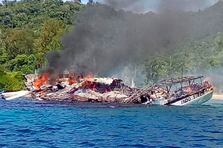 A burnt out dive boat, with smoke rising