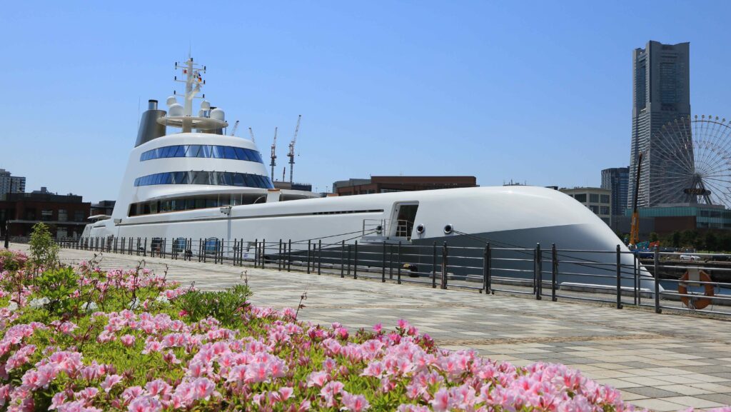 Eine Superyacht liegt in Japan vor Anker, im Vordergrund sind Blüten zu sehen