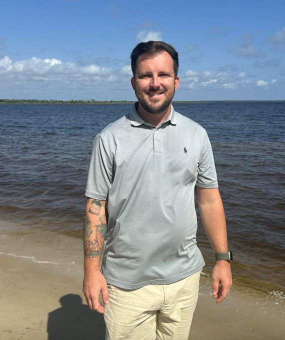 A man smiles at the camera - wearing a t-shirt on the beach. Jesse Carpenter joins Highfield Boats as it takes on four new dealers