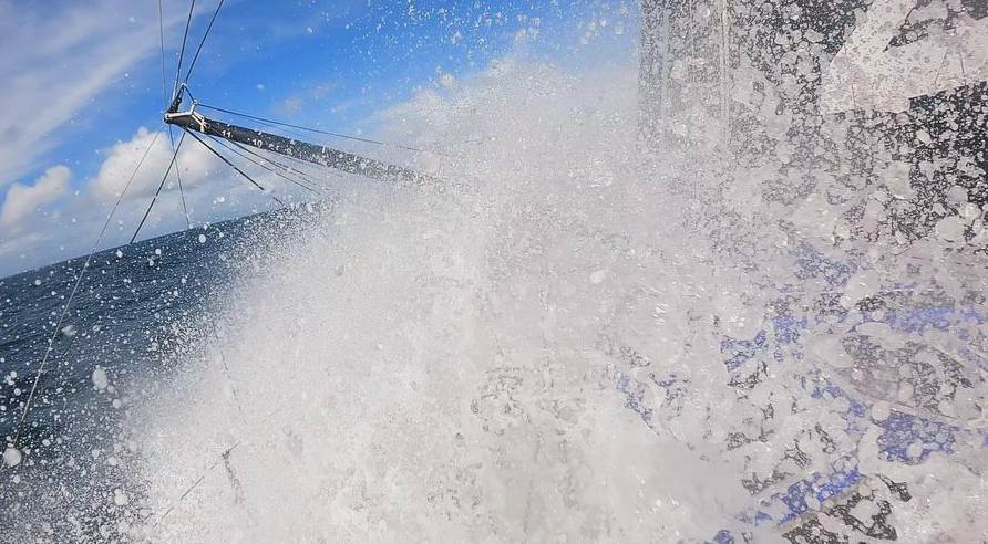 Waves crash over Pip Hare's IMOCA which she is getting ready for the Vendée Globe