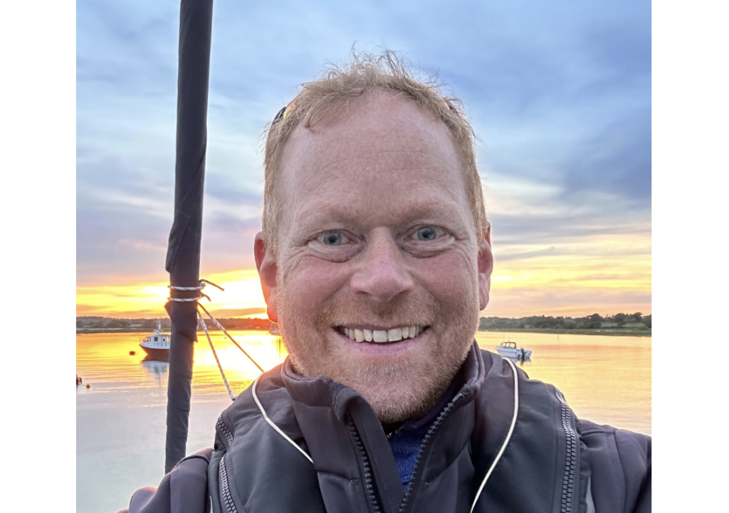 mans face selfie with sea and sunset in background