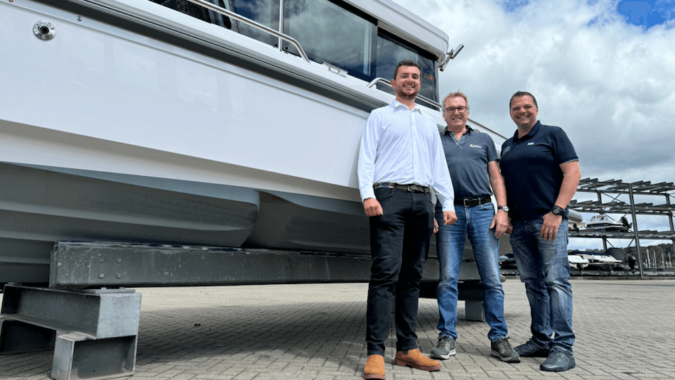 Three men stand in front of a boat