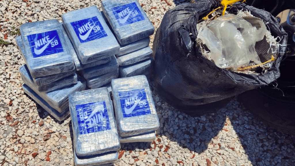 pacotes de cocaína encontrados em praia na Flórida. Eles têm o logotipo azul da Nike e são retratados ao lado de um saco de lixo preto