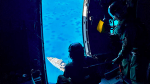 People in helicopter look down on Fiji navy patrol ship grounded on a reef