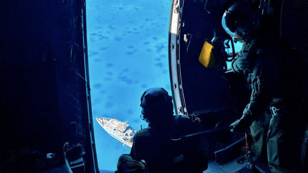 People in helicopter look down on Fiji navy patrol ship grounded on a reef