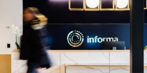 Woman walks by a desk with Informa logo in background