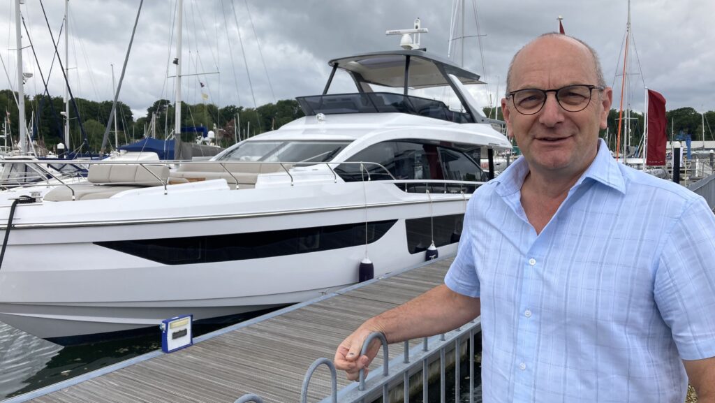 Robert Parton British Marine president looks at camera. He's standing i front of a boat while he considers marine strategy for UK with new government being formed