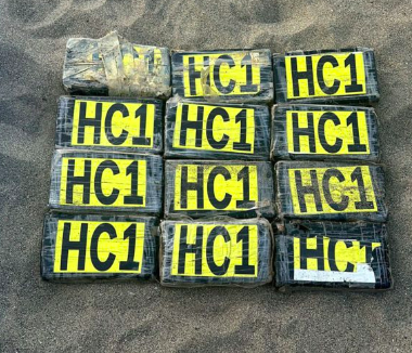 Packets of drugs - thought to be cocaine or heroin - stacked on sand after boat found with 14 deceased