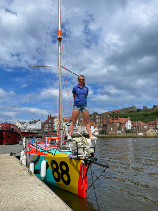 Sailor stands on mini boat which she will sail solo around world