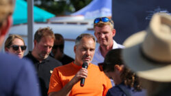 Man in orange t shirt talking to small group of people at a boat show